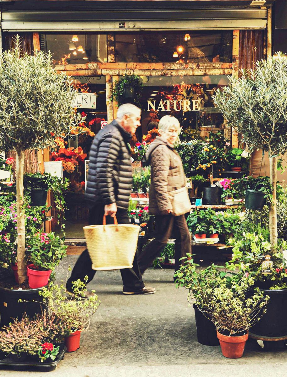 Ein Seniorenpaar geht an einem Blumenladen vorbei.