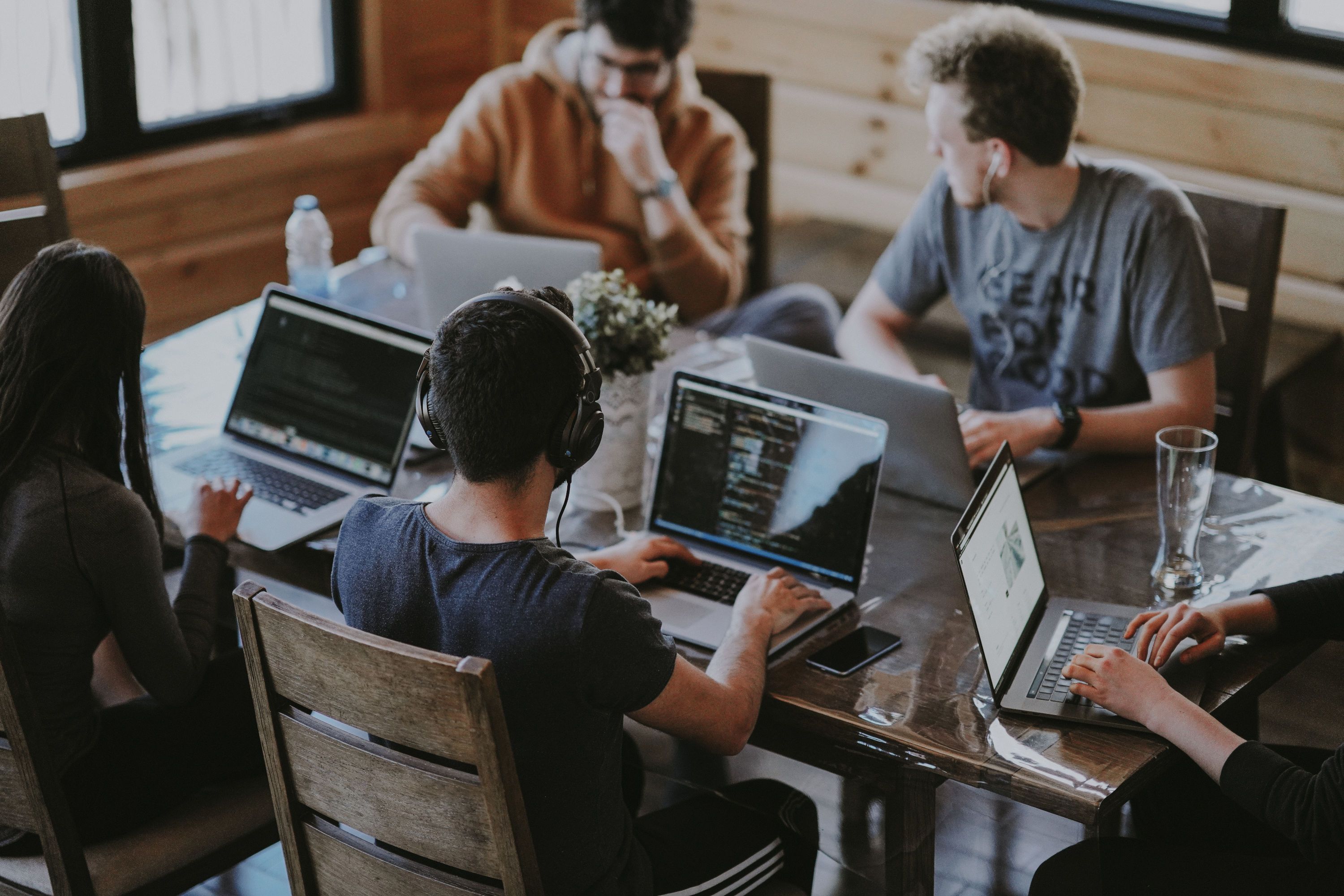 Vier Menschen sitzen am Tisch vor ihren Laptops und arbeiten.