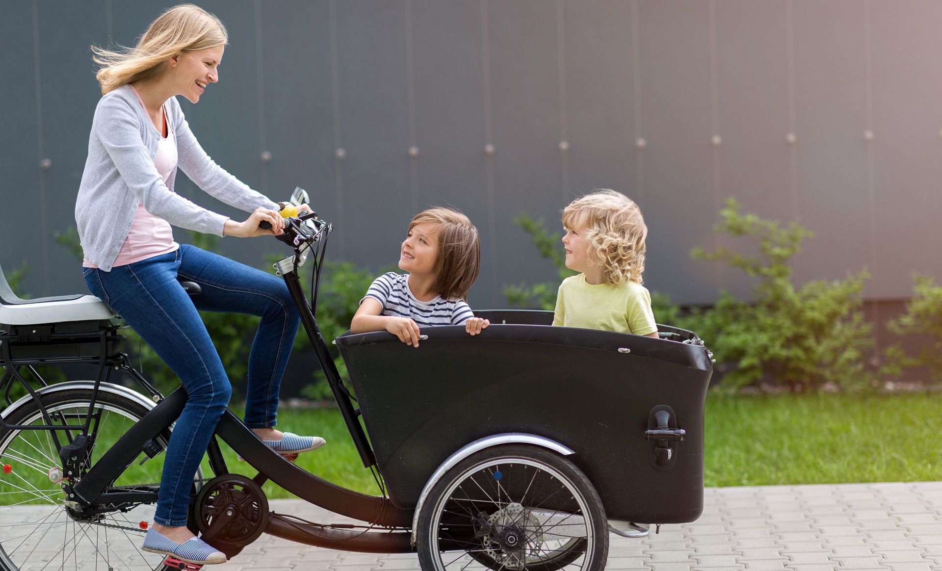 Frau mit Lastenfahrrad und zwei Kindern